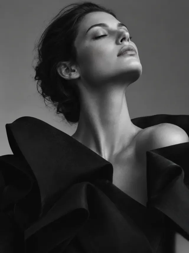 Black and white portrait of an adult model wearing a sculptural black garment